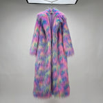 Load image into Gallery viewer, A long, shaggy faux-fur coat hanging against a gray paneled wall. The coat has a multicolor pastel rainbow pattern with prominent pink, blue, purple, and yellow tones.
